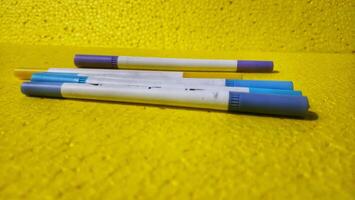 three pens laying on a yellow surface photo