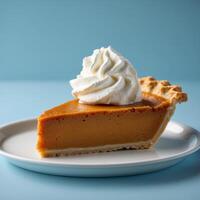 A Delicious Slice of Pumpkin Pie with Whipped Cream on a Blue Background photo