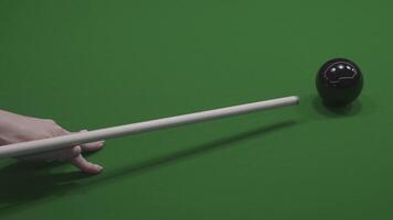 A detailed closeup image showing a pool cue striking a black ball on a green table surface video