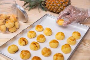 Hand Picking Freshly Baked Nastar Cookies from Tray to Glass Jar photo