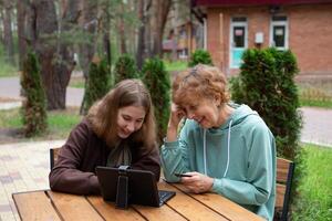 a younger woman assisting an older woman with a tablet and credit card information. photo