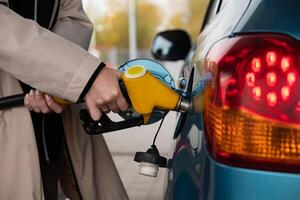 Pumping gas at the gas pump. at a gas station. A woman refuels a car with gasoline at a gas station. Fuel injection into the tank. Detail of a woman filling a car with diesel fuel photo