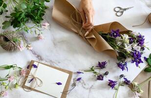 A florist is crafting a bouquet of delicate purple and white flowers on a marble tabletop. photo