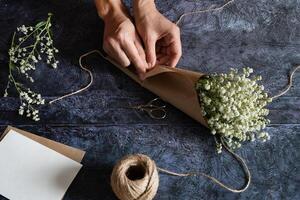 A floral arrangement is underway, with hands skillfully tying a bouquet of fresh flowers on a marble surface. photo