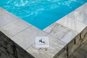 Wet floor plate is near swimming pool. photo