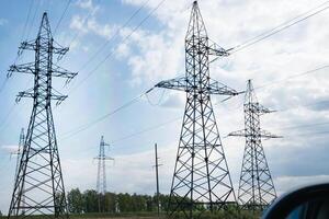 power pylons in a flat and green agricultural landscape on a sunny day with cirrus clouds in the blue sky. photo