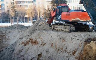 Excavator during earthmoving en pit on blue sky background. Construction machinery and earth-moving heavy equipment for excavation, photo