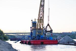 Barge loading sand by the crane. River in mountain region in Vietnam photo