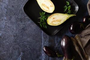 Assortment raw organic of purple vegetables mini eggplants, spring onion, beetroot, radicchio salad, plums, kohlrabi, flower salt over dark metal background. Top view with space. Food frame photo