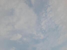 A soft, cloudy sky with gentle shades of blue and white, creating a peaceful and dreamy atmosphere. The clouds spread across the sky in a delicate, airy pattern. photo