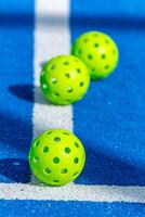 three pickleball balls on the line in a blue court, racket sports concept background photo