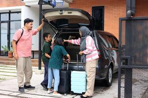 Indonesian Young Family Preparing for Trip in front of Their House, with Suitcases photo