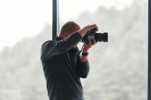 A professional photographer is captured working in his studio by a window, skillfully capturing a business photoshoot with precision and creativity. photo