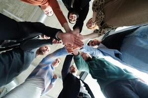 A group of business professionals, captured from a low angle, holding hands to symbolize unity and teamwork. photo