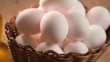 Fresh white eggs displayed in a woven basket on a wooden surface video