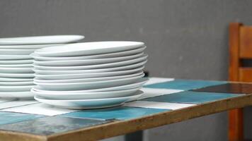 Stacked white plates on a colorful table in a cozy setting video
