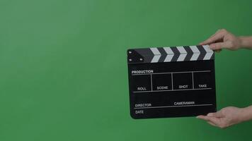 black and white film clapperboard or movie slate being held in front of a green screen. Essential filmmaking tool is used to mark scenes and synchronize audio and vid in film production. video