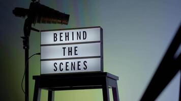 Behind the scene light box. front of vdo camera frame. Black text on white lightbox of word Behind the scenes. Prop for filmmaker movie or film studio. Footage for B roll film production making of. video