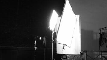 VDO production studio lighting setup with diffuser softbox continuous lights and equipment stands against a dark backdrop. Ideal for photography filmmaking and commercial vdo production footage. video