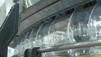 Close up view of plastic bottle production line in a factory. Parts of transparent PET bottles move along an automated conveyor system. Showing modern PET drinking bottles manufacturing automation video