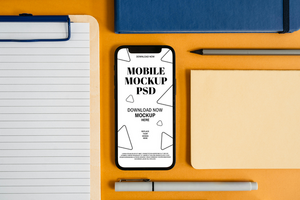 Smartphone mobile mockup with paper pen and notebook on the desk psd