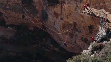 Group assists jumper for an extreme rope swing from a cliffside platform video