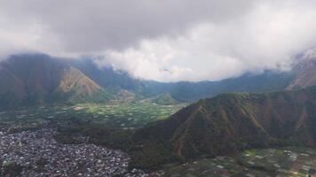 Aerial view of valley with green fields and cloudy mountains in Lombok video