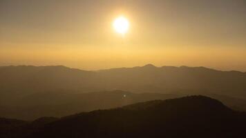 The setting sun shines down on a serene mountain landscape covered with tropical trees. photo