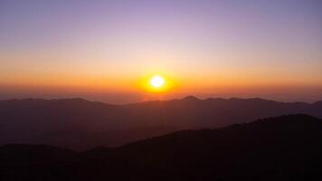 sunset The setting sun shines down on a serene mountain landscape covered with tropical trees in the evening. photo