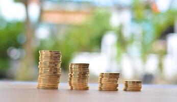 A pile of gold coins on a table with a bokeh background photo