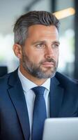 Businessman in a classic suit works on a laptop in the office. Confident look, serious expression. The concept of business, leadership, success and professionalism. photo