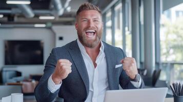 Satisfied businessman in a suit exults in front of a laptop in a modern office. photo