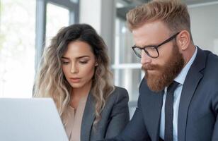 Businessman and businesswoman at a laptop in a modern office. Confidence, success and productivity at work. Business communications, strategy discussion and cooperation in a corporate environment. photo