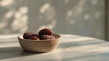 A bowl containing fresh dates is placed on a textured surface, illuminated by soft morning light creating gentle shadows. Ramadan banner with copy space. photo