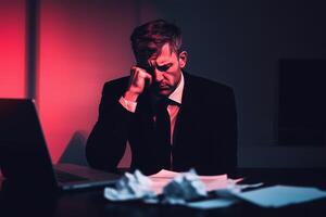 Stressed businessman in a dark office, surrounded by crumpled papers, symbolizing despair, pressure, and inner struggle. A powerful metaphor for burnout and mental breakdown. . photo
