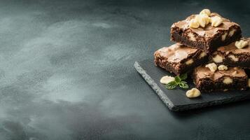 A stack of rich chocolate brownies neatly arranged on a slate board ready to tempt dessert lovers with their indulgence photo