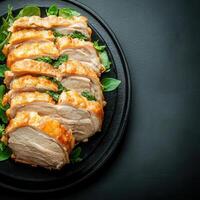 Flavorful plate of grilled chicken on a black plate showcasing juicy meat accompanied by colorful garnishes photo