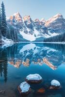 Snowy mountains reflect in lake water. Winter trees line the lake shore. Rocks with snow sit in water. A peaceful landscape scene. photo