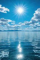 Ocean water under bright sun. Sky with clouds reflection on surface. Light sparkles on ripples and waves. Tranquil clear blue color day. photo