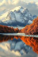 Snow mountain shines. Orange trees line calm water. Reflection shows mountain and sky. Peaceful nature image. Scenic landscape. Autumn view. photo