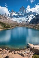 Mountain peak with snow. Blue lake below. Rocks near the water. Clear sky above. Beautiful landscape scenery. photo