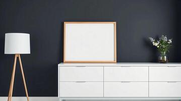 A white dresser and a wooden lamp in front of a black wall photo