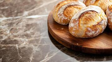 Fresh bread on wooden plate on marble counter photo