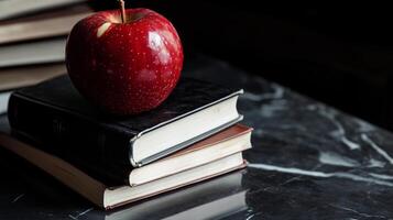 A crimson apple perched atop a pile of books photo