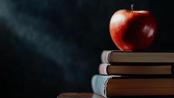 An apple red sits on top of a stack of books photo