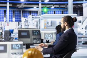 Engineer in solar panel manufacturing facility reviewing photovoltaic system performance on PC. Specialist analyzing production metrics to optimize efficiency in industrial renewable energy plant photo