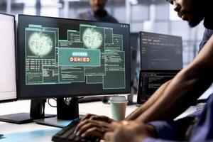Computer scientist in server farm fighting hacker managing to pass firewall and stealing data. Employee receiving access denied notification on PC display in data center facility photo