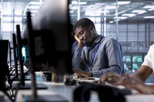 Bored data center engineer mindlessly using programming languages to construct algorithms and build applications. Fatigued server room employee tired of debugging and optimizing code photo