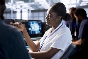 Smiling woman talking with colleague in server room, creating high performance AI systems on PC. Cheerful admin in data center discussing with coworker, developing artificial intelligence photo