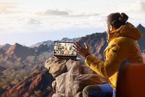 Adventure seeker employee meeting with workmates on call, enjoying strong signal at internet on top of the mountain. Male explorer entrepreneur with technology dependency. photo